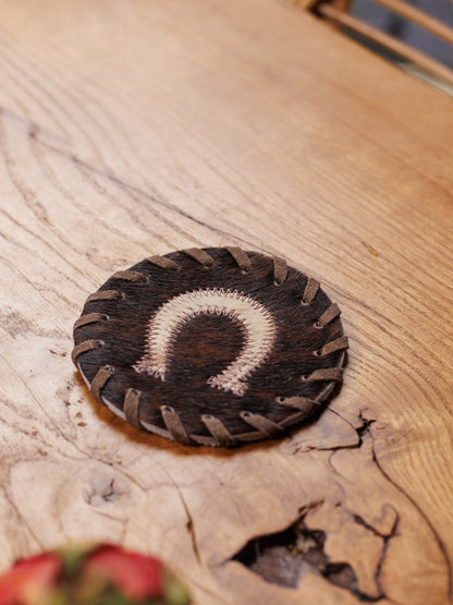 Koeienhuid onderzetter met hoefijzer op een houten tafel, van dichtbij